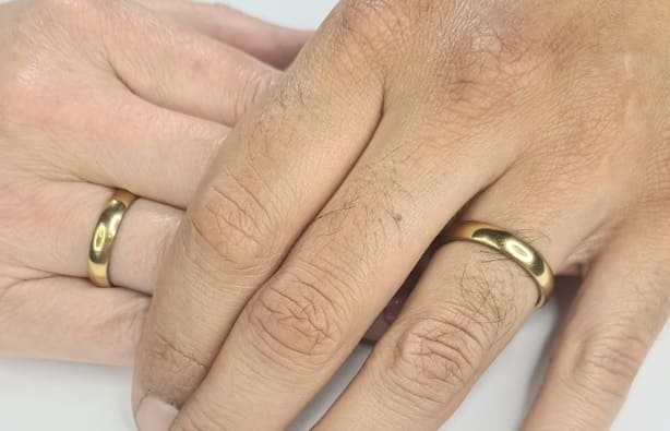 Manos de hombre y mujer con anillos alianza en dedo anular